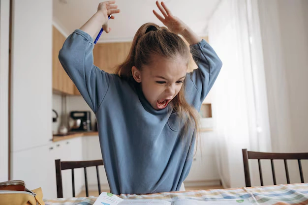 Child showing behavioral challenges and frustration during learning activity at home