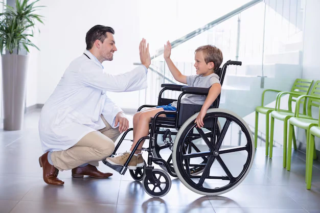 Doctor encouraging a child in a wheelchair during therapy session to support rehabilitation and confidence