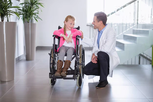 Doctor interacting with a child in a wheelchair to support physical and developmental therapy